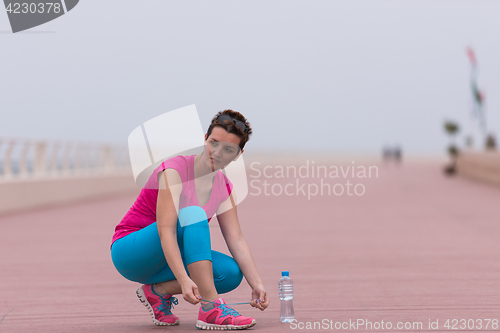 Image of Young woman tying shoelaces on sneakers