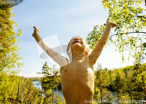 Image of little cute real boy among tree hight, outdoor lifestyle concept close up