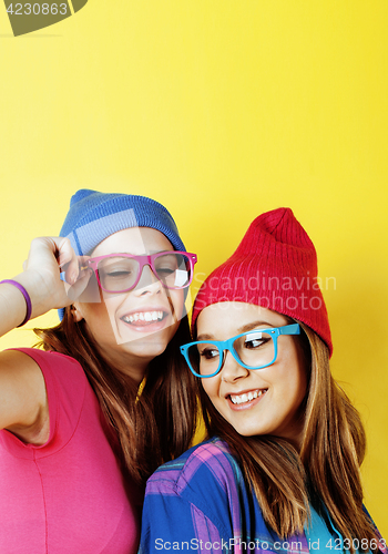 Image of lifestyle people concept: two pretty young school teenage girls having fun happy smiling on yellow background 
