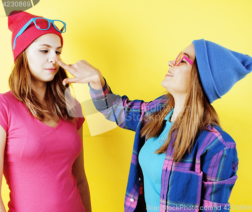 Image of lifestyle people concept: two pretty young school teenage girls having fun happy smiling on yellow background 