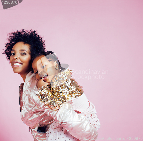 Image of young pretty african-american mother with little cute daughter hugging, happy smiling on pink background, lifestyle modern people concept 