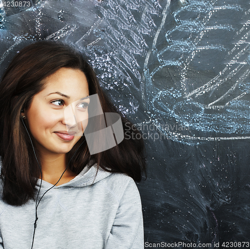 Image of young cute teenage girl in classroom at blackboard seating on ta