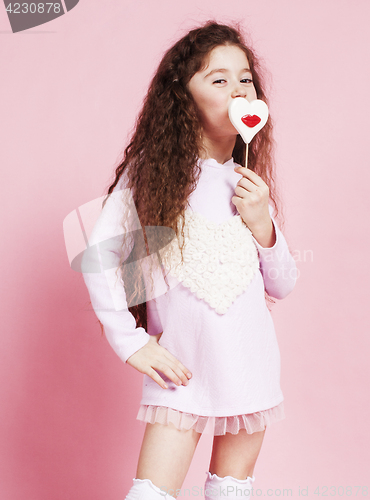 Image of little cute girl with candy on pink background posing emotional, lifestyle people concept