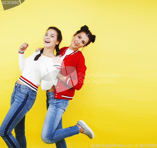 Image of lifestyle people concept: two pretty young school teenage girls having fun happy smiling on yellow background 
