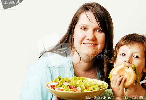 Image of mature woman holding salad and little cute boy with hamburger te