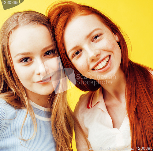 Image of lifestyle people concept: two pretty young school teenage girls having fun happy smiling on yellow background