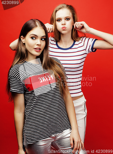 Image of two best friends teenage girls together having fun, posing emotional on red background, besties happy smiling, lifestyle people concept