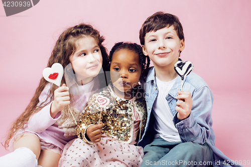 Image of lifestyle people concept: diverse nation children playing together, caucasian boy with african little girl holding candy happy smiling 