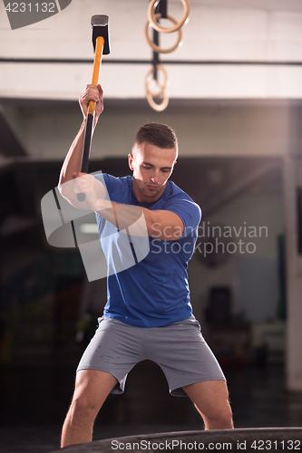 Image of man workout with hammer and tractor tire