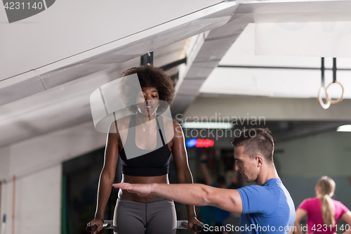 Image of black woman doing parallel bars Exercise with trainer