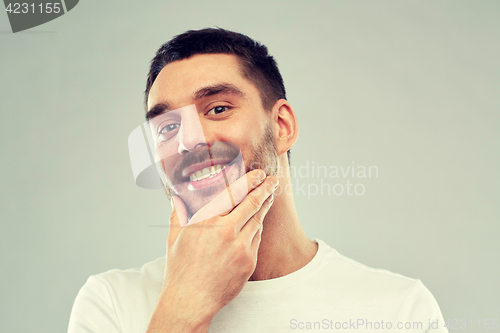 Image of happy young man touching his face or beard