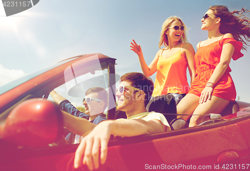 Image of happy friends driving in cabriolet car