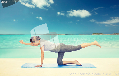 Image of woman making yoga in balancing table pose on mat