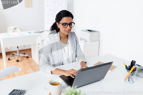 Image of happy smiling businesswoman with laptop at office