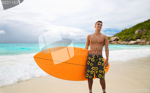 Image of smiling young man with surfboard on summer beach