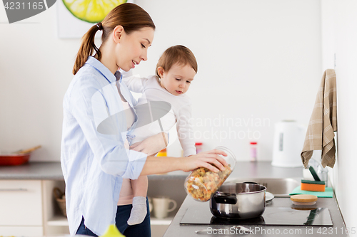 Image of mother and baby cooking pasta at home kitchen