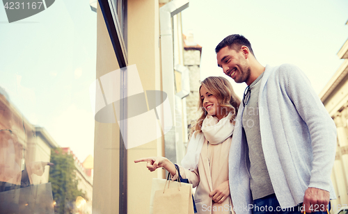 Image of happy couple with shopping bags at shop window