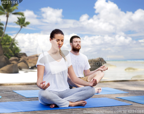 Image of people meditating in yoga lotus pose outdoors