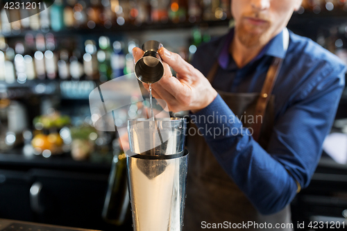 Image of barman with shaker preparing cocktail at bar