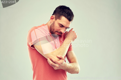 Image of unhappy man suffering from pain in hand