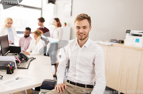 Image of happy young man over creative team in office