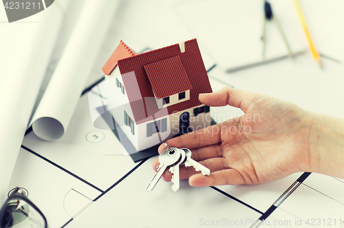 Image of close up of hand with house keys and blueprint