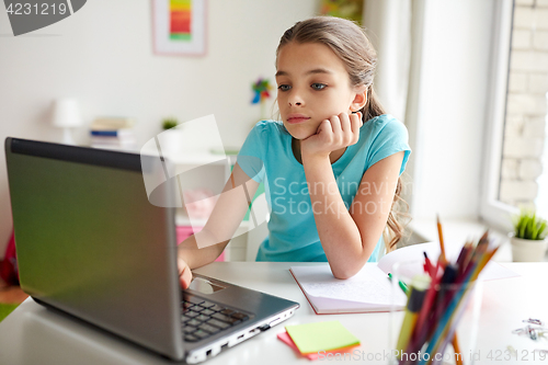 Image of bored girl with laptop and notebook at home