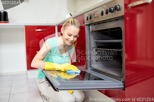 Image of happy woman cleaning cooker at home kitchen