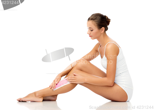 Image of woman removing leg hair with depilatory wax strip