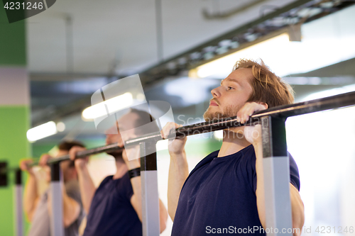 Image of group of young men doing pull-ups in gym