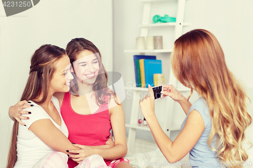 Image of teen girls with smartphone taking picture at home