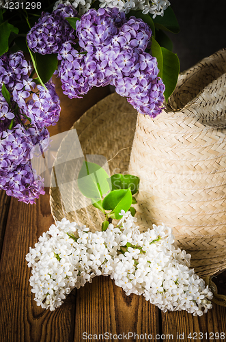 Image of Still-life with a bouquet of lilacs and a straw hat, close-up