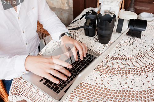 Image of Man working on laptop at the wooden table outdoors