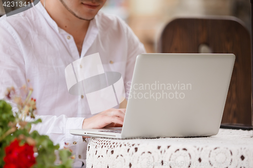 Image of Man working on laptop at the wooden table outdoors