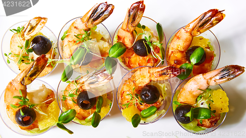 Image of Shrimp, avocado, tomato, salmon cocktail salad served in a glass.