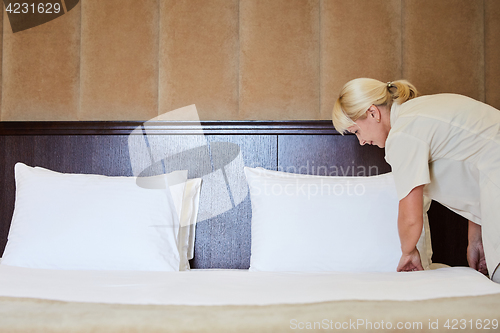 Image of Hotel service. Made making bed in room.