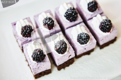 Image of The rows of sweet and tasty cakes with blackberries.