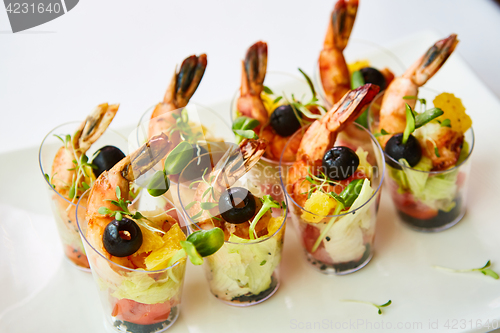 Image of Shrimp, avocado, tomato, salmon cocktail salad served in a glass.