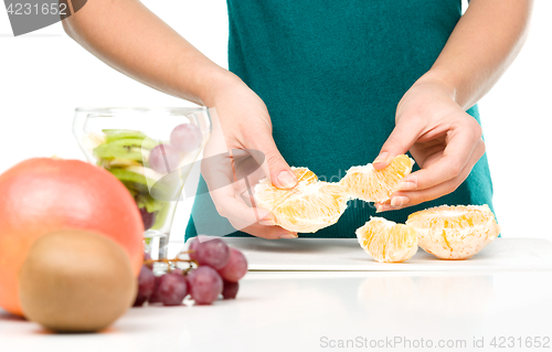 Image of Cook is tearing orange for fruit dessert