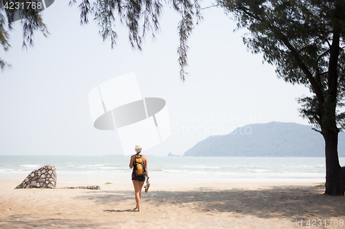 Image of Young brunette walking along beach