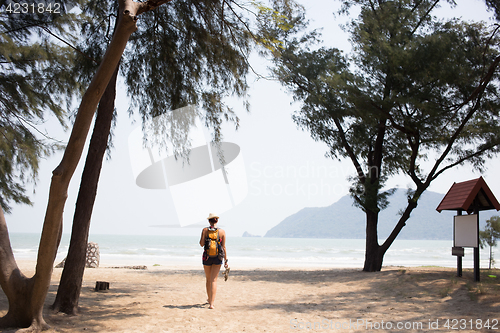 Image of Young woman walks along beach