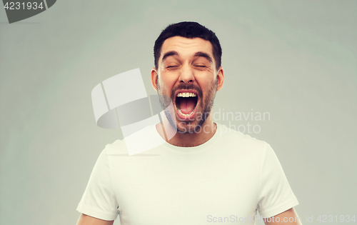 Image of crazy shouting man in t-shirt over gray background