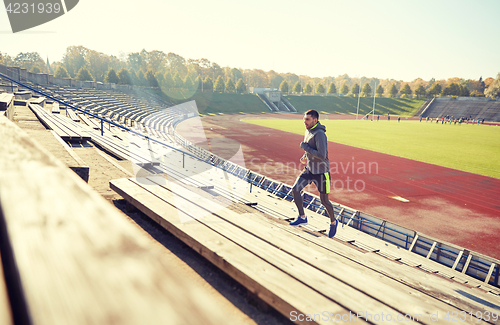 Image of happy young man running upstairs on stadium