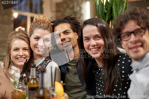 Image of happy friends with drinks at bar or cafe