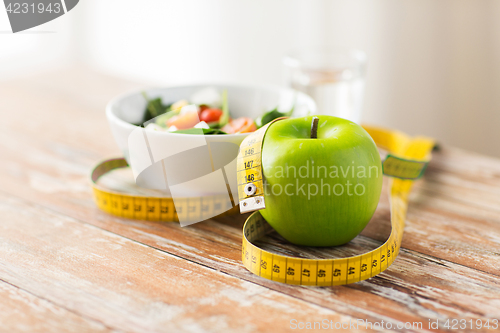 Image of close up of green apple and measuring tape