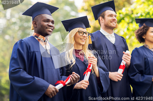 Image of happy students in mortar boards with diplomas