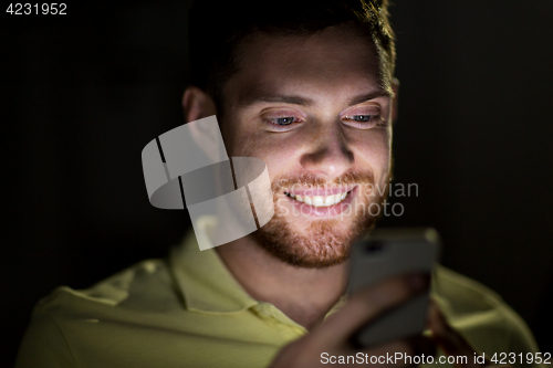 Image of happy young man with smartphone at night