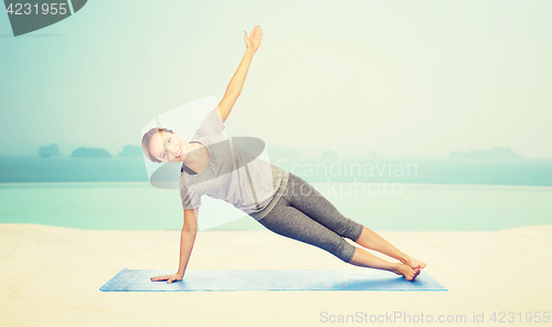 Image of woman making yoga in side plank pose on mat