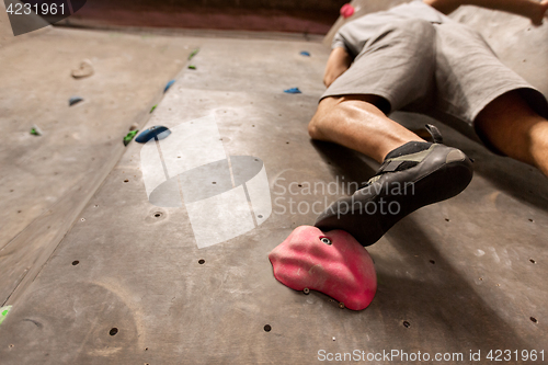 Image of foot of man exercising at indoor climbing gym