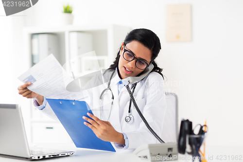 Image of doctor with clipboard calling on phone at hospital